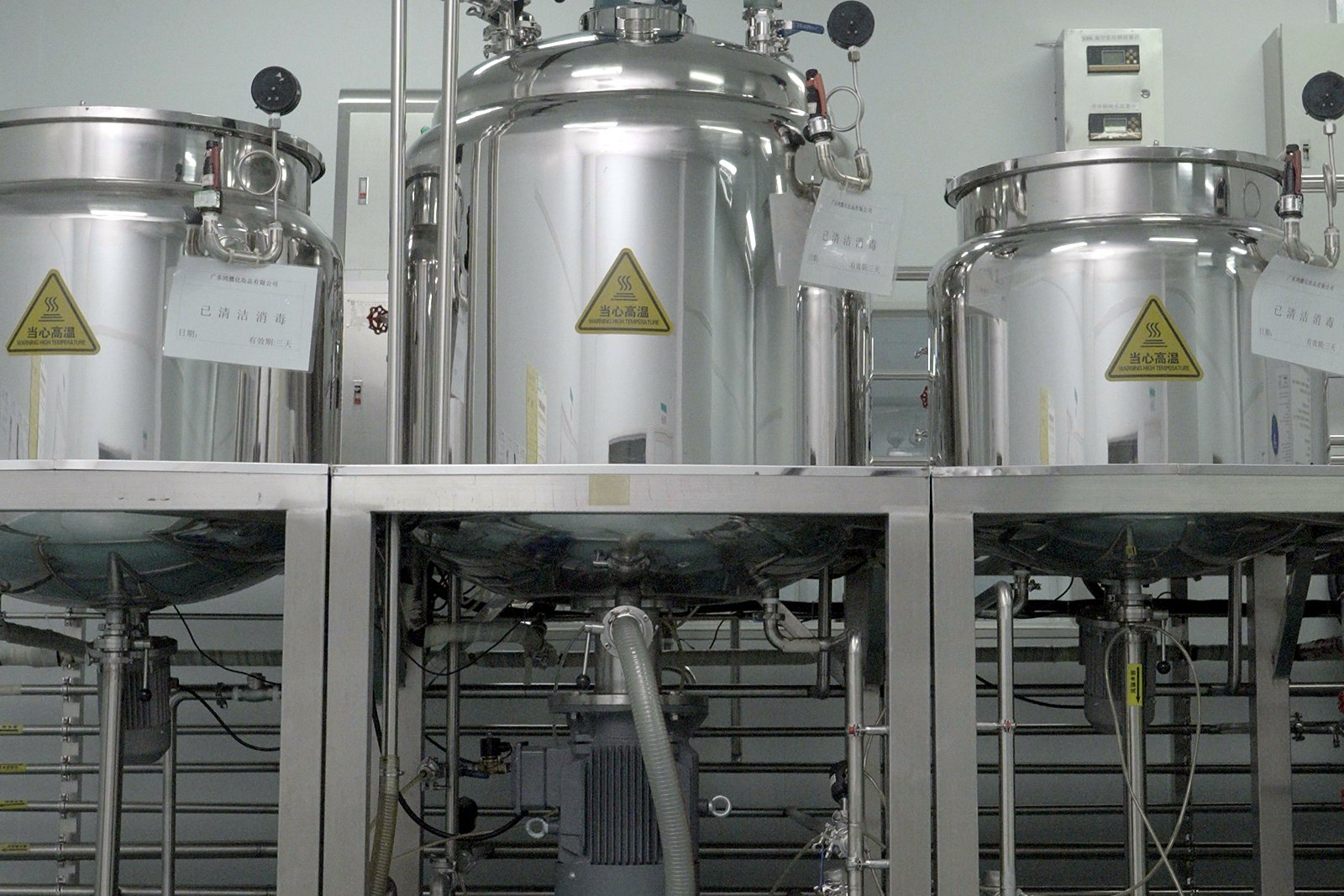 Three stainless-steel processing vessels with control fittings on the production floor
